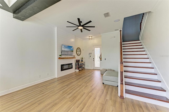 living room with a fireplace, ornamental molding, ceiling fan, and light wood-type flooring