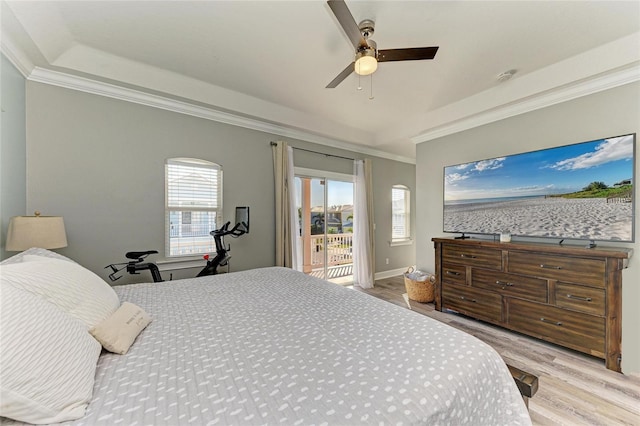 bedroom with ornamental molding, access to outside, ceiling fan, a tray ceiling, and light wood-type flooring