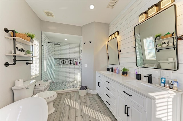 bathroom featuring vanity, toilet, a shower with door, and a wealth of natural light