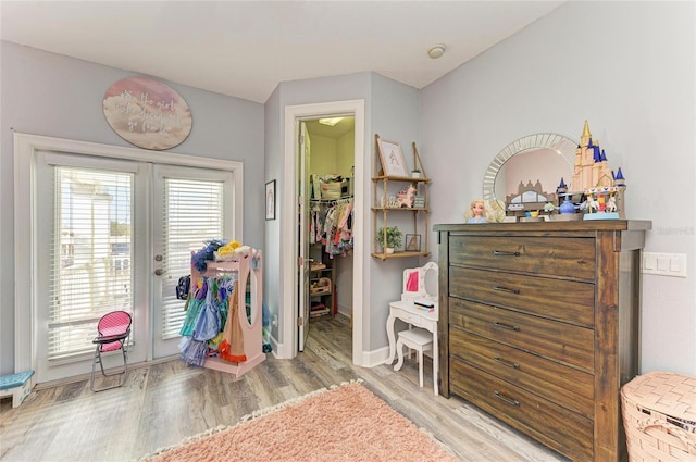 interior space with french doors, a walk in closet, light hardwood / wood-style flooring, and access to outside