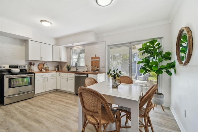 kitchen featuring white cabinetry, appliances with stainless steel finishes, wooden counters, and light wood-type flooring