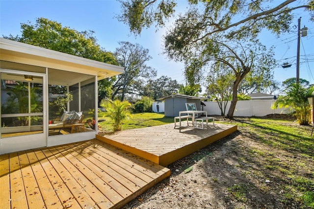 deck with a sunroom, a lawn, and a shed