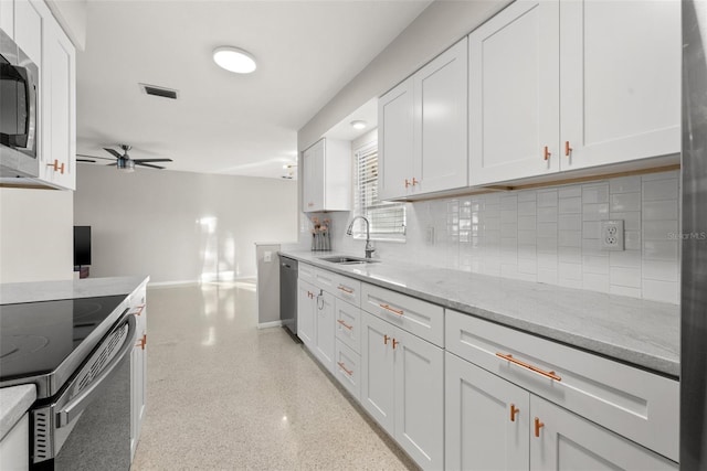 kitchen with stainless steel appliances, light stone countertops, sink, and white cabinets