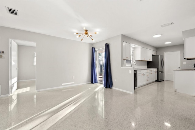 kitchen featuring stainless steel refrigerator, white cabinetry, black dishwasher, sink, and an inviting chandelier