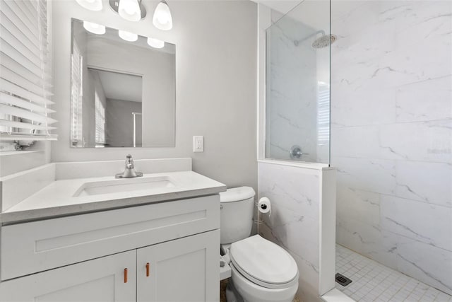 bathroom with vanity, toilet, and a tile shower