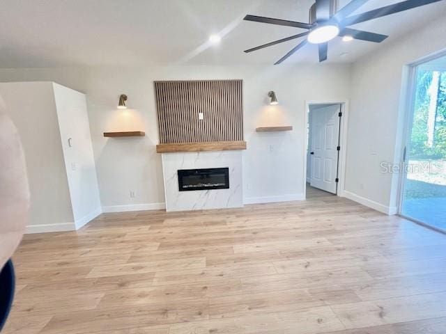 unfurnished living room with ceiling fan, a fireplace, and light hardwood / wood-style flooring