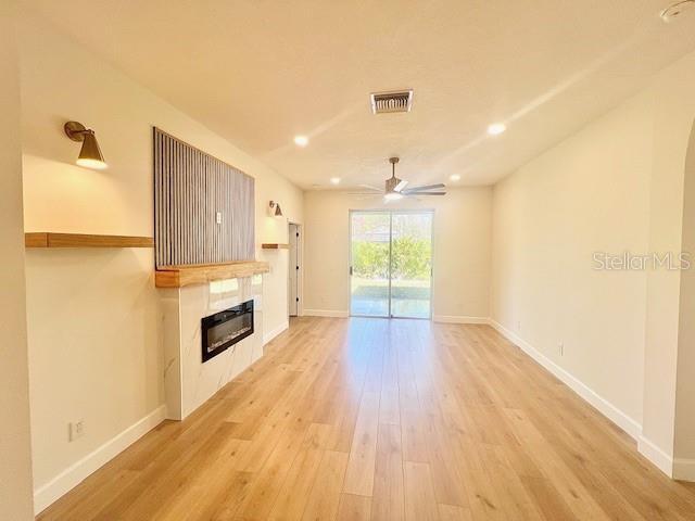 unfurnished living room with light hardwood / wood-style flooring and ceiling fan