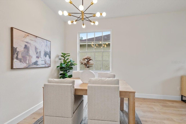 dining area with light hardwood / wood-style floors and a notable chandelier