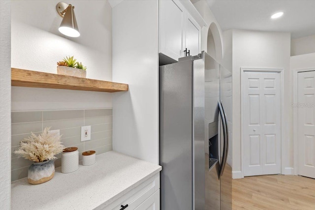 kitchen featuring white cabinetry, stainless steel fridge, tasteful backsplash, and light hardwood / wood-style flooring