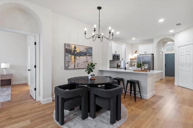 dining area with an inviting chandelier and light hardwood / wood-style floors