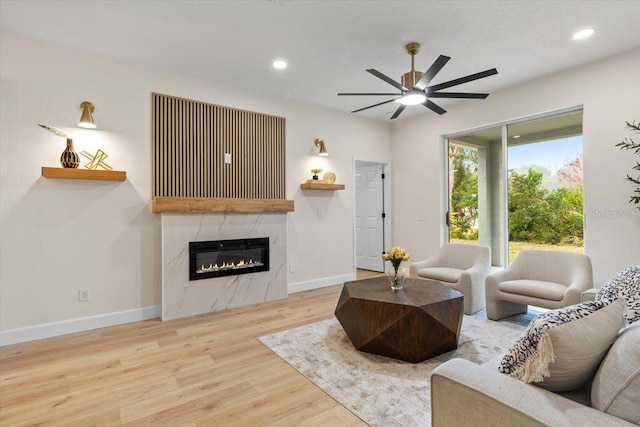 living room featuring hardwood / wood-style flooring, a high end fireplace, and ceiling fan