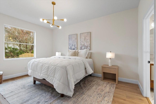 bedroom with an inviting chandelier and light hardwood / wood-style flooring