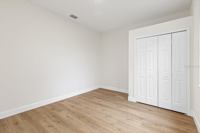 unfurnished bedroom featuring light wood-type flooring and a closet