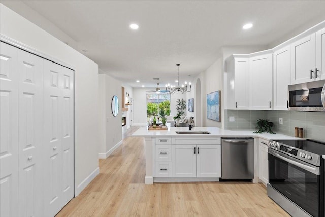 kitchen with pendant lighting, white cabinetry, kitchen peninsula, and appliances with stainless steel finishes