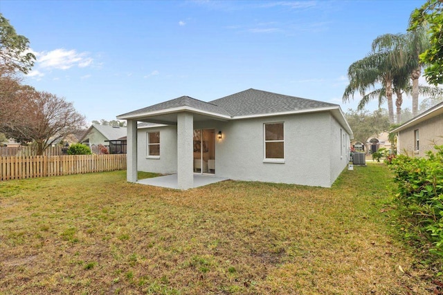 rear view of house with central AC, a patio area, and a lawn