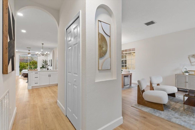 hallway featuring a notable chandelier and light wood-type flooring