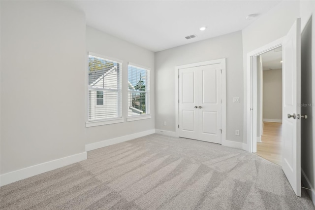 unfurnished bedroom featuring a closet and light colored carpet