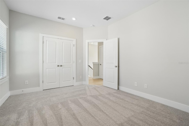 unfurnished bedroom with a closet and light colored carpet