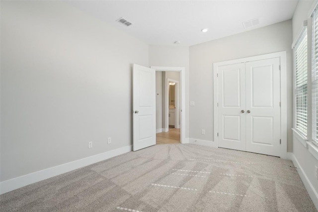 unfurnished bedroom with a closet and light colored carpet