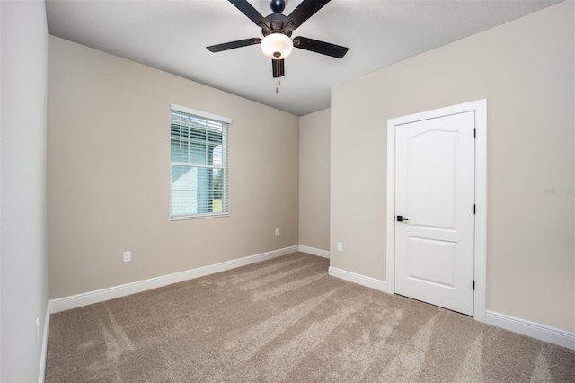 carpeted spare room featuring ceiling fan