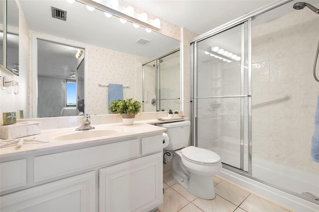 bathroom with tile patterned floors, toilet, a shower with shower door, and vanity