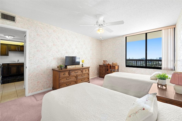 carpeted bedroom featuring sink, ensuite bath, a textured ceiling, and ceiling fan