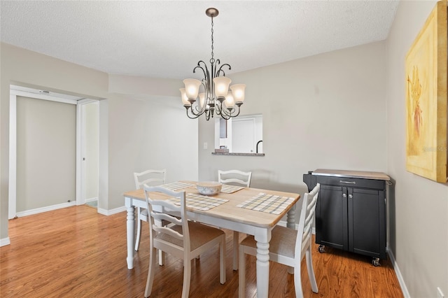 dining room featuring an inviting chandelier, a textured ceiling, and light wood-type flooring