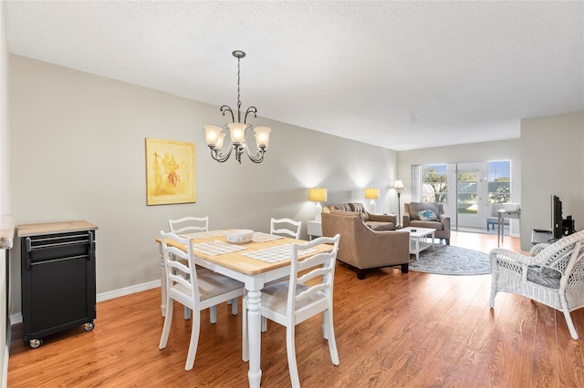 dining area with a chandelier, light hardwood / wood-style floors, and a textured ceiling