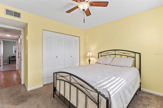 carpeted bedroom with ceiling fan, a closet, and a textured ceiling