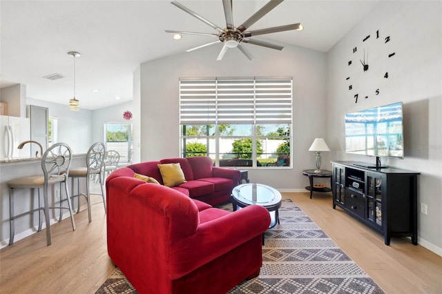 living room featuring lofted ceiling and light hardwood / wood-style floors