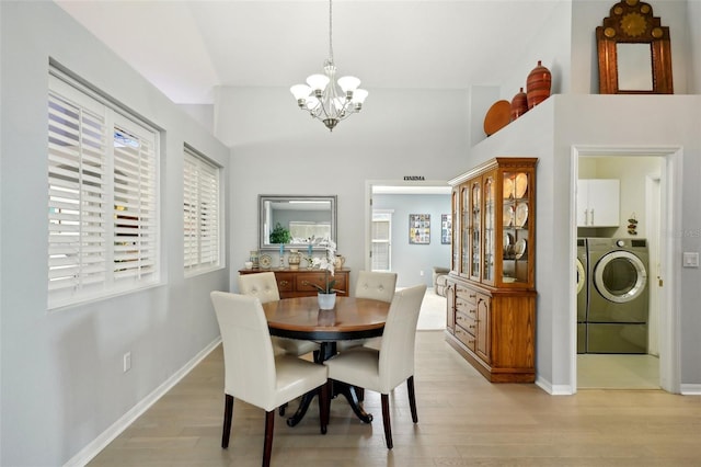 dining room with a notable chandelier, washer and dryer, and light wood-type flooring