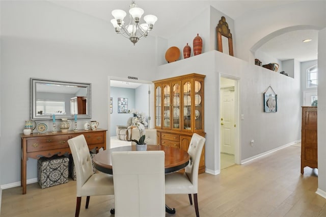 dining space featuring a notable chandelier, a high ceiling, and light wood-type flooring