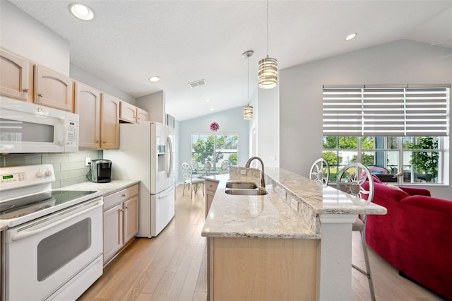 kitchen featuring lofted ceiling, sink, decorative light fixtures, light brown cabinets, and white appliances