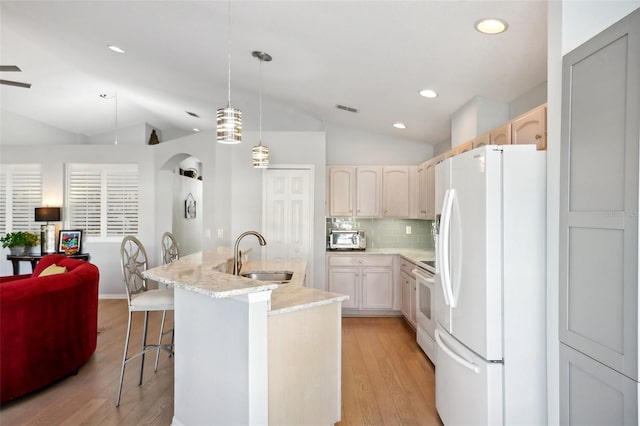 kitchen featuring sink, white appliances, a kitchen island with sink, hanging light fixtures, and vaulted ceiling