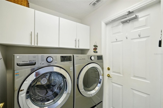 clothes washing area featuring cabinets and washing machine and clothes dryer