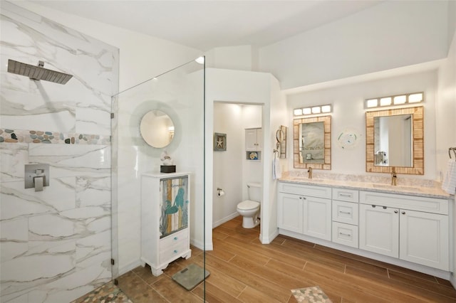 bathroom featuring vanity, toilet, and a tile shower