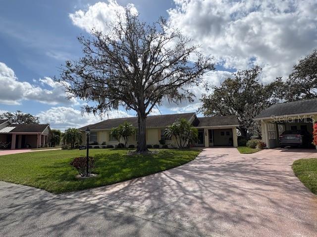 ranch-style home featuring a garage, decorative driveway, and a front lawn