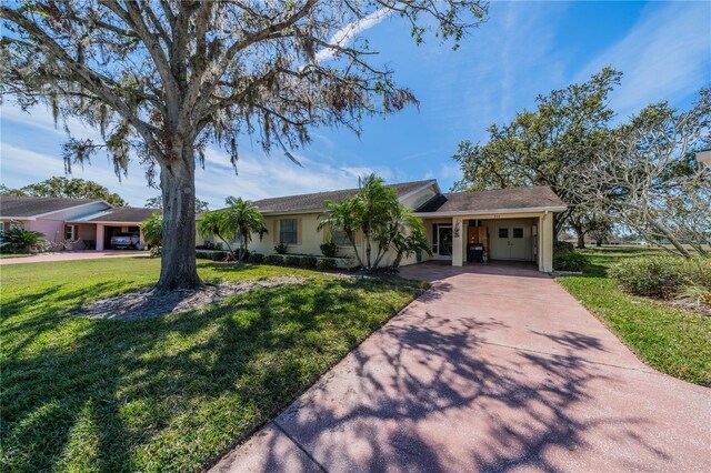 ranch-style home featuring driveway, a front lawn, an attached carport, and stucco siding