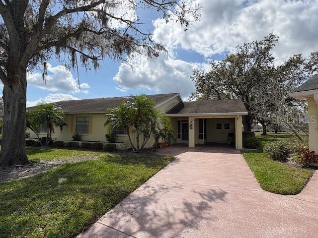 ranch-style home with a front yard, driveway, and stucco siding