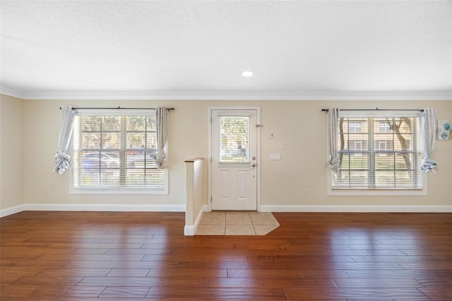 foyer featuring ornamental molding, dark hardwood / wood-style flooring, and a textured ceiling