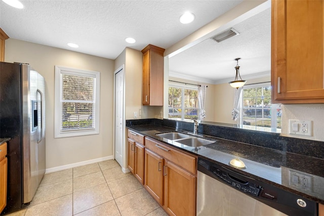 kitchen featuring sink, decorative light fixtures, light tile patterned floors, appliances with stainless steel finishes, and dark stone counters