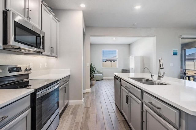 kitchen with light wood-type flooring, sink, gray cabinets, and appliances with stainless steel finishes