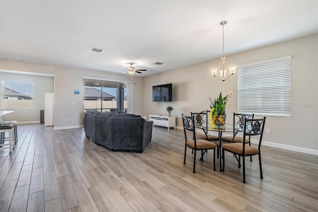 dining room featuring plenty of natural light, ceiling fan with notable chandelier, and light hardwood / wood-style flooring