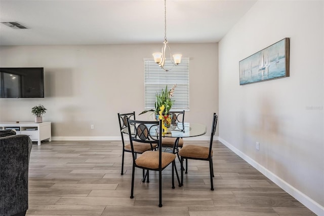 dining room with light hardwood / wood-style flooring and a chandelier