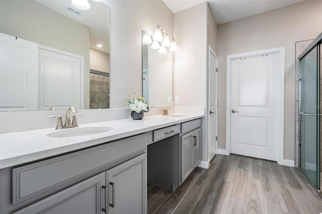 bathroom featuring wood-type flooring, a shower with door, and vanity