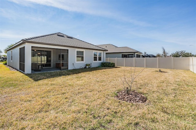 back of property with a sunroom and a yard