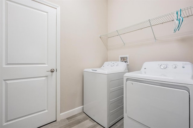 clothes washing area with washer and dryer and light wood-type flooring