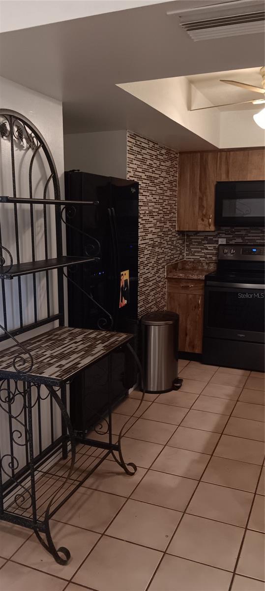 kitchen featuring ceiling fan, light tile patterned floors, and black appliances