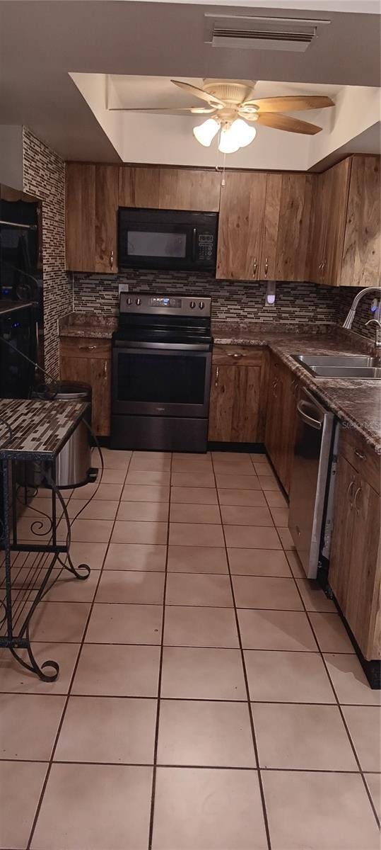 kitchen with appliances with stainless steel finishes, sink, light tile patterned floors, and backsplash