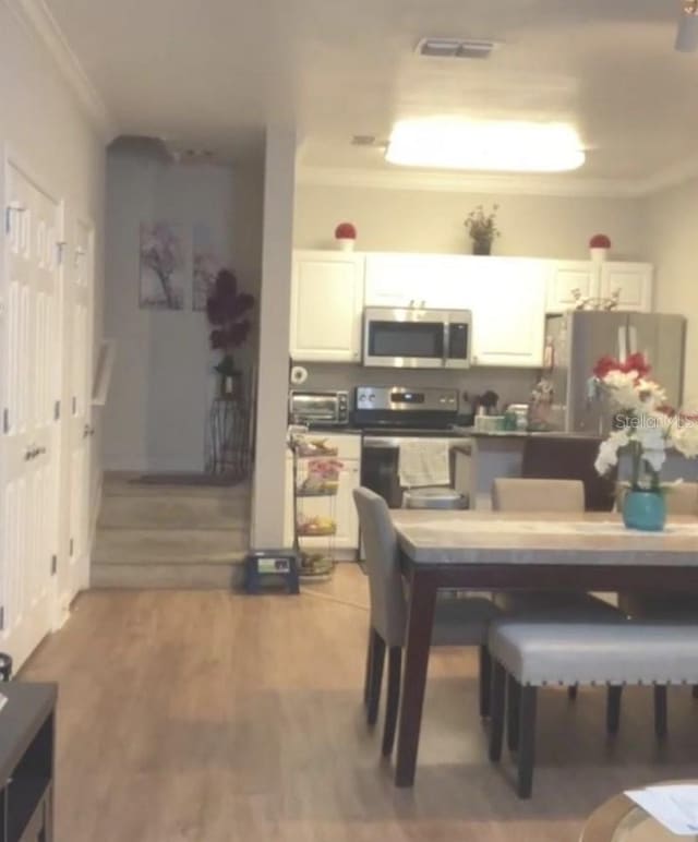 dining area featuring hardwood / wood-style flooring and ornamental molding